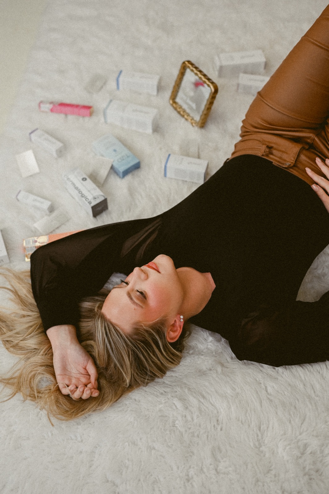 Bailee Newsome lying on a white rug surrounded by skincare products